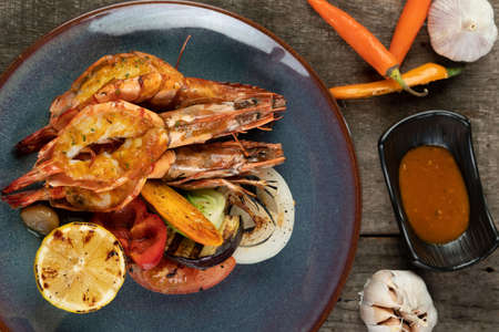Wok-fried prawns with garlic and chili isolated on wooden rustic tableの写真素材