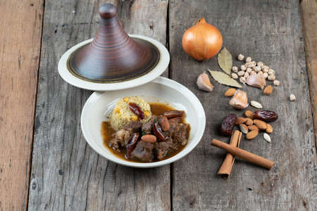 Slow cooked lamb with potato and dates served with warm couscous and chickpeas isolated on the wooden tableの写真素材