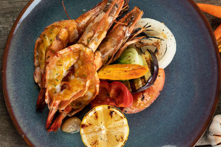 Wok-fried prawns with garlic and chili isolated on wooden rustic tableの写真素材