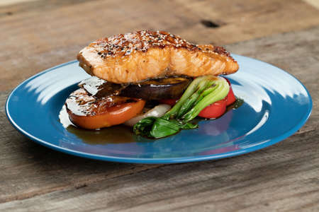 Grilled Salmon steak with vegetables isolated on rustic wooden tableの写真素材