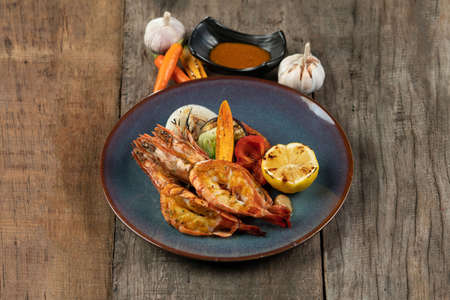 Wok-fried prawns with garlic and chili isolated on wooden rustic tableの写真素材