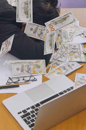 businessman slepping with heap of dollar money in office