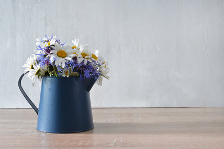 Bouquet of wildflowers in blue vase on wooden tableの写真素材