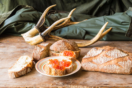 Sandwiches with red caviar and deer antlers on a wooden table
