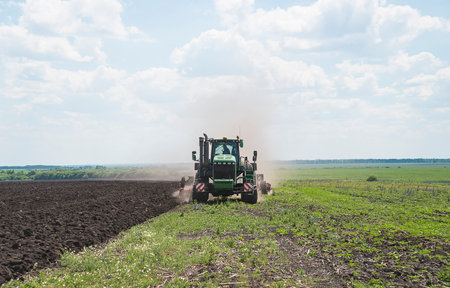 Tractor spraying pesticides on soybean field with seedbed cultivatorの写真素材