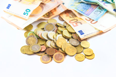 Euro coins and banknotes of different denominations on a white background.の写真素材