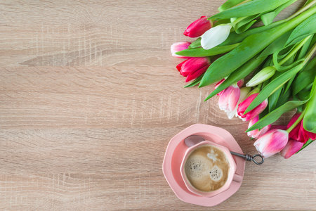 Cup of coffee and bouquet of tulips on wooden backgroundの写真素材