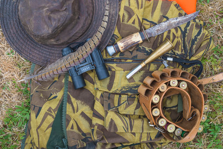 Hunting equipment and ammunition in the field. Hunter hat, binoculars and hunting knife.