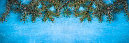 Christmas background with fir branches on a blue wooden background. top view.