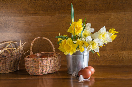 Bouquet of daffodils and easter eggs on a wooden backgroundの写真素材