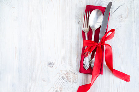 Vintage cutlery with red ribbon on white wooden background.の写真素材