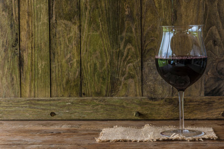 Glass of red wine on a rustic wooden table with copy spaceの写真素材