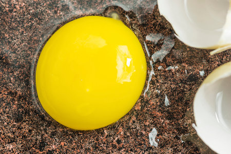 Egg yolk in a broken eggshell on a granite background