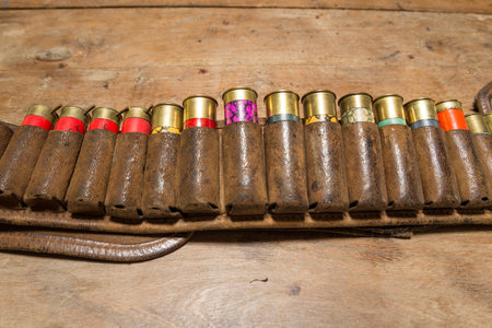 Bullets in a leather case on a wooden background. Selective focus.