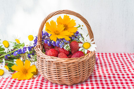 Strawberries in a basket with daisies and wildflowersの写真素材