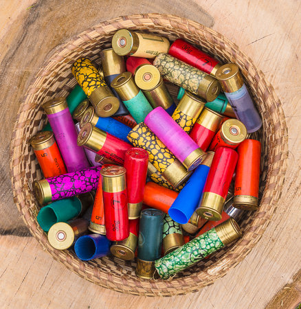 Colorful cartridges of different sizes in a wooden basket on a wooden background
