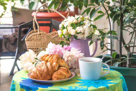 Breakfast with coffee, croissants and flowers in the gardenの写真素材