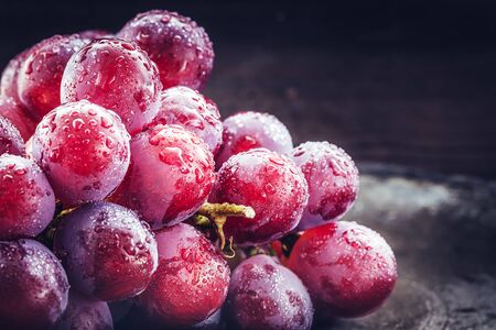 Close-up of fresh, dark red grapes with water splashes on dark backgroundの写真素材