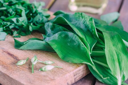 Fresh green ramson with buds on wooden background.