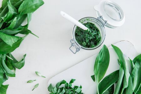 A glass of pesto with green wild garlic on a white table, top viewの写真素材