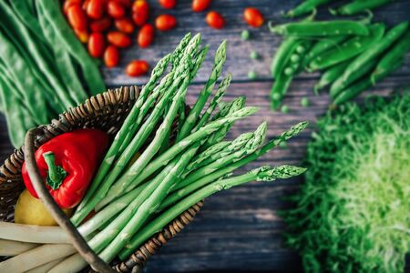 Vegetables in basket on wooden background. fresh raw food. top view. focus on the foregroundの写真素材