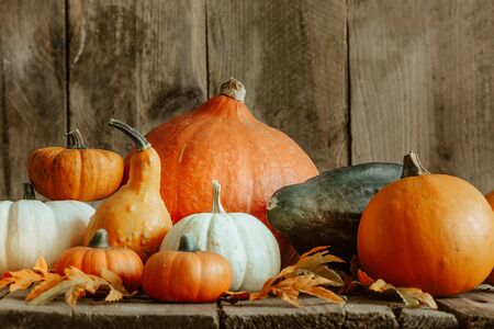 Autumn still life with pumpkins and leaves on old wooden background