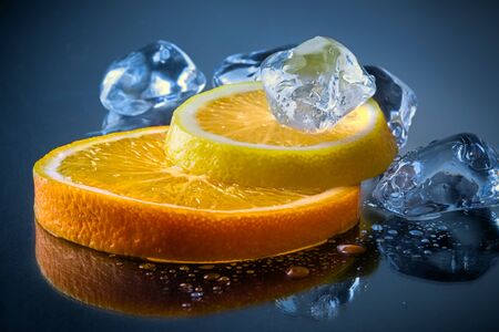 cut lemons with lemon slices and ice cubes against dark background. Top view. Close-up