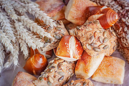 Assortment traditional breads and buns with grains on a wooden board. Top view.の写真素材