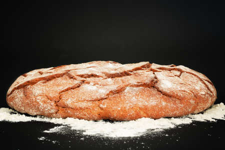 A large rustic sourdough bread with crispy crust. Rye bread on dark floured