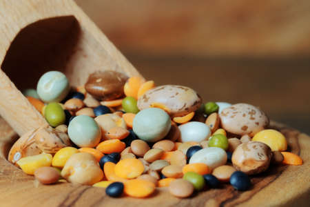 Selection of different legumes in a wooden bowl with a wooden spoon. close up.