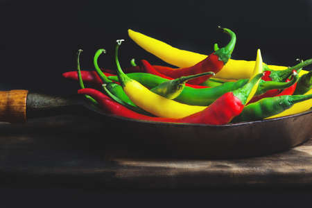 Coloful peppers in a skillet, black backgroundの写真素材