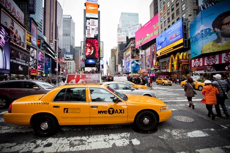 NEW YORK - DECEMBER 17: Yellow cab speeds through Times Square the busy tourist intersection of neon...