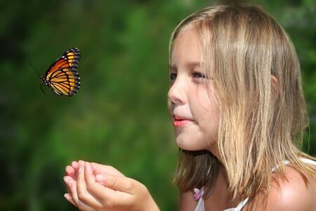 Young girl enjoying spring with a butterflyの写真素材