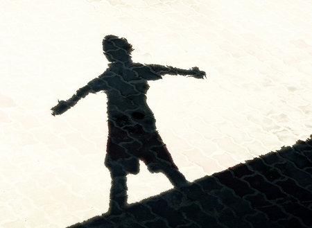 Shadow of boy standing with arms outstretchedの写真素材