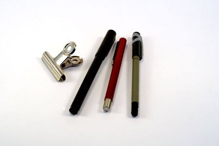 Pens and paper clip on a white background