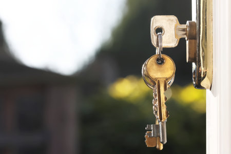 House keys in lock of a door viewed outside with soft glow background from natural lighting. Room for text.の写真素材