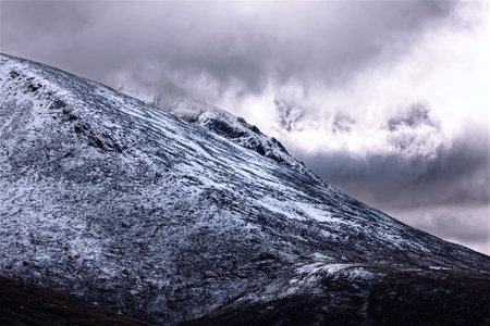 Ben Nevis, Scottish Highlands, the highest mountain in the UK, under stormy sky in winter weather landscape. The sun is breaking through the clouds.の写真素材