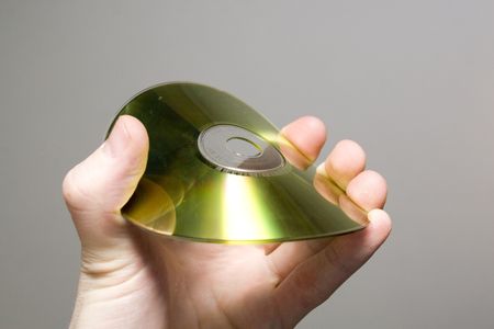 Golden compact disk being bent in a man's hand