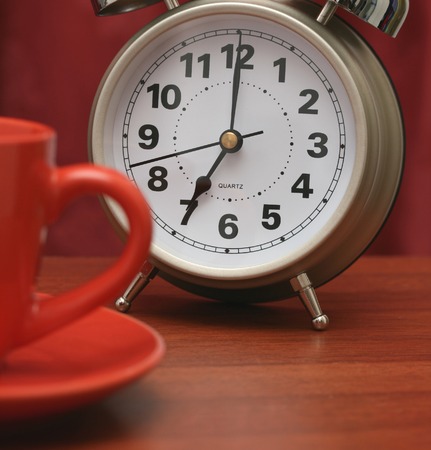 Alarm clock with a red cup and a saucer.