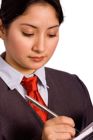 A woman in a business suit writing down her weekly schedule on an organizerの写真素材