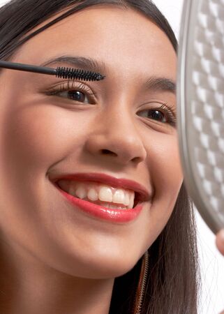 smiling young girl applying a black mascara