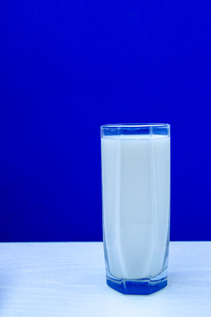 Glass of milk on white wooden table. Minimal concept.の写真素材