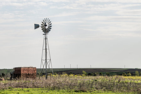 Windmill pumping water in the wide open spaces of North Texas under a cloudy skyの写真素材