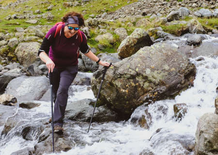 Solo female hiker crossing a stream.のeditorial素材