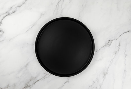 Top view of black plate on white marble background. Food presentation flat lay. Copy space.の写真素材