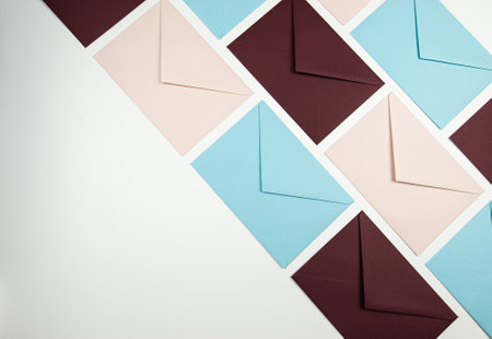 Top view of colourful envelopes on white background. Pink, blue, dark red envelopes flat lay. Post, copy space.の写真素材