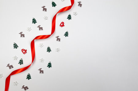 Christmas composition, red ribbon and confetti on white background. Shiny rolled fabric, silk and satin material. Top view, flat lay, copy space.の写真素材