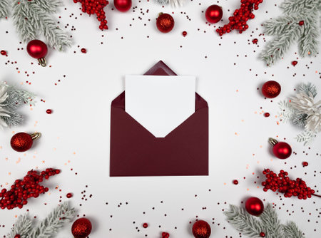 Christmas composition, red envelope, fir tree branches, red berries, baubles and stars confetti on...