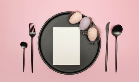 Top view of easter eggs, feathers, white card, black plate and cutlery on pink background. Creative easter composition, spring, flat lay, copy space.の写真素材