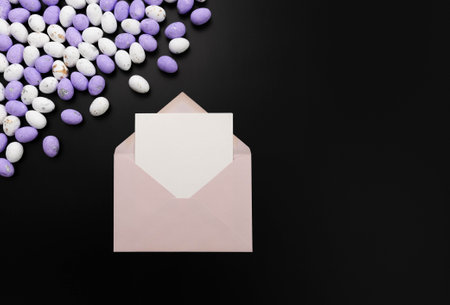 Top view of purple and white easter eggs, pink envelope, white card on black background. Creative easter composition, spring, copy space, flat lay.の写真素材
